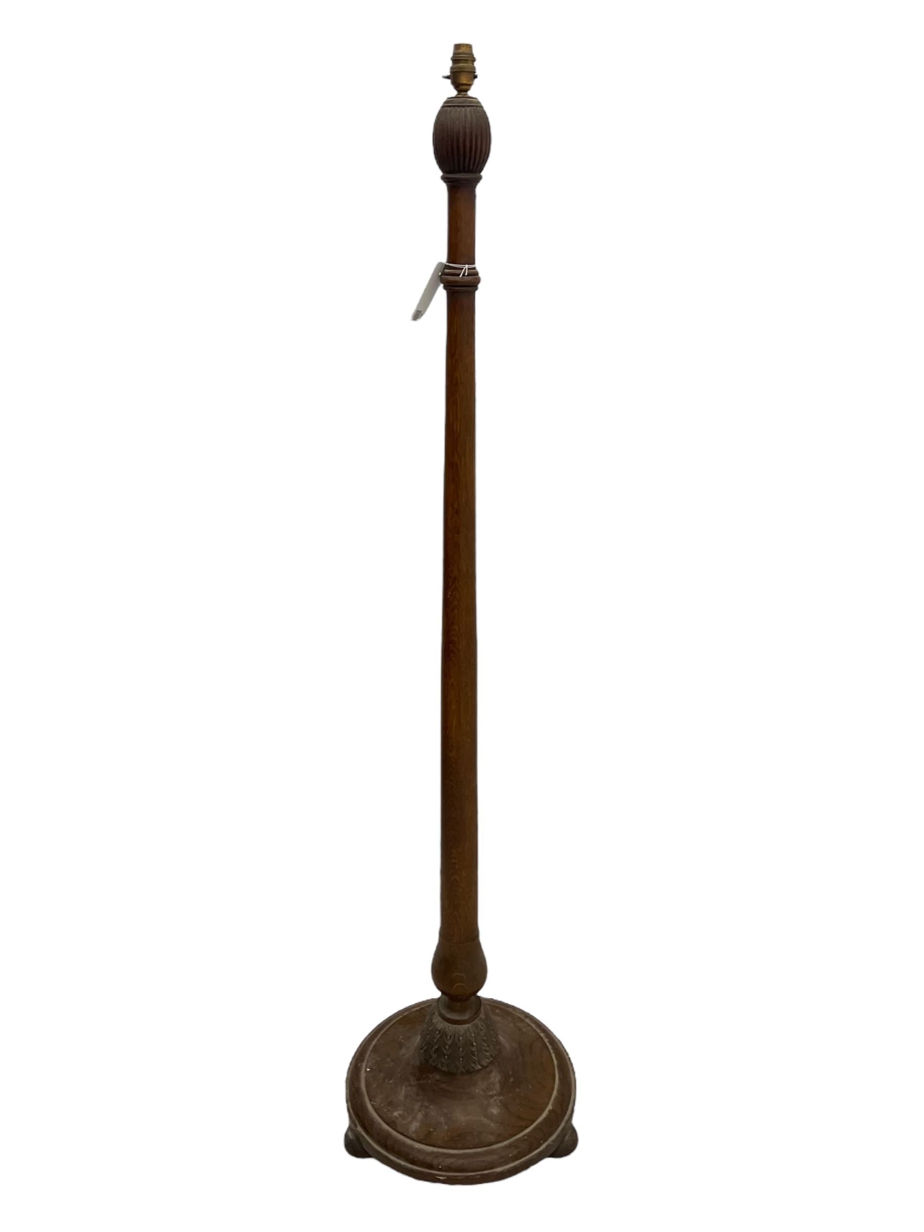 Early 20th century oak standard lamp base, of baluster form with fluted acorn finial and carved foliate decoration to the base, raised on circular plinth with bun feet