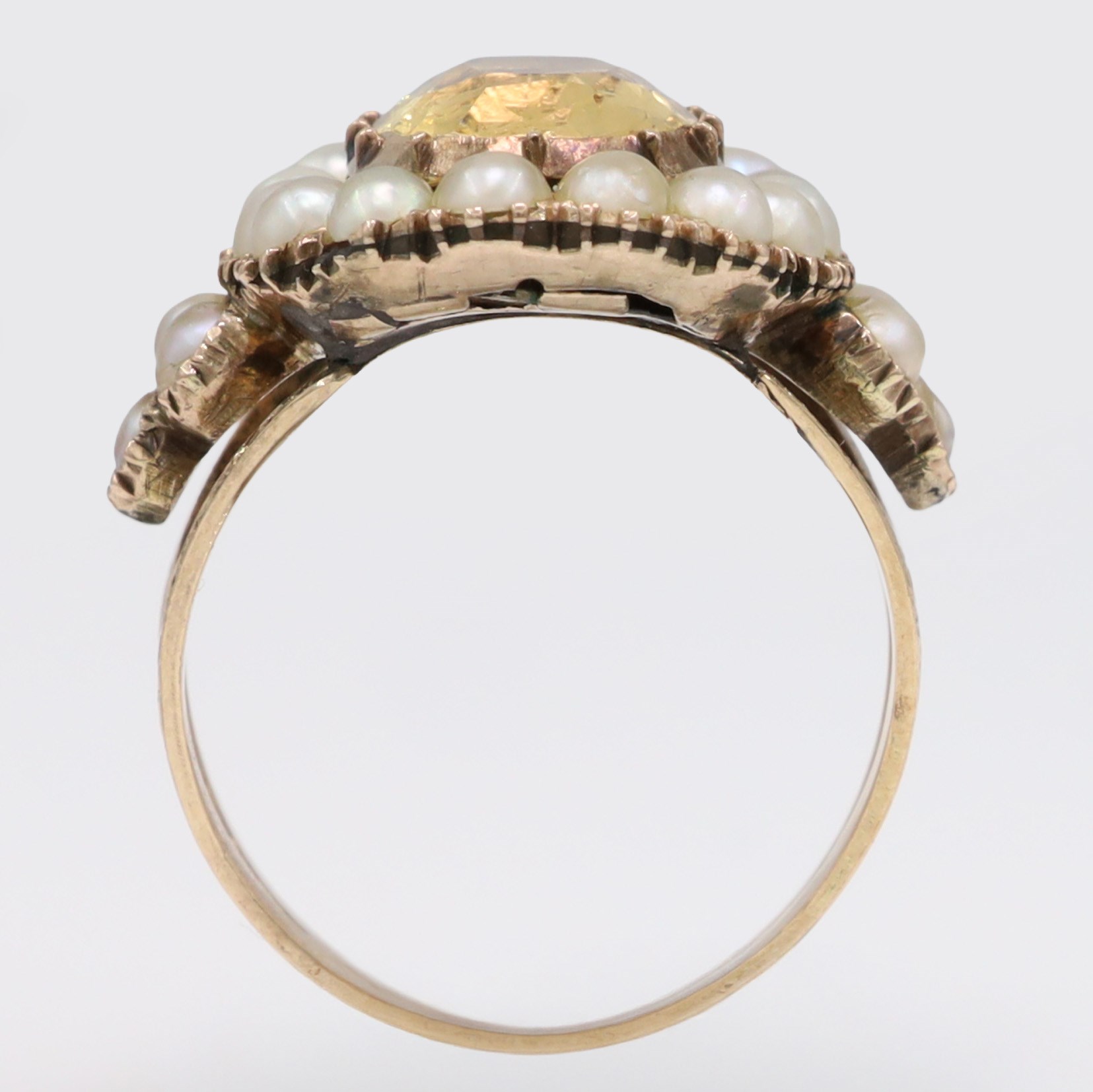 Georgian gold yellow topaz (possibly imperial) and split pearl cluster ring, collect set with a single oval cut foiled back topaz, surrounded by fifteen pearls and pearl set scroll engraved trefoil shoulders