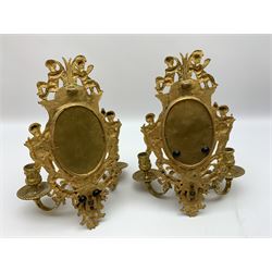 Pair of 19th century ormolu three branch wall sconces, the oval bevelled edge mirror backs within frame flanked and surmounted by putti, supporting three scrolling branches above female mask terminals, H32cm 