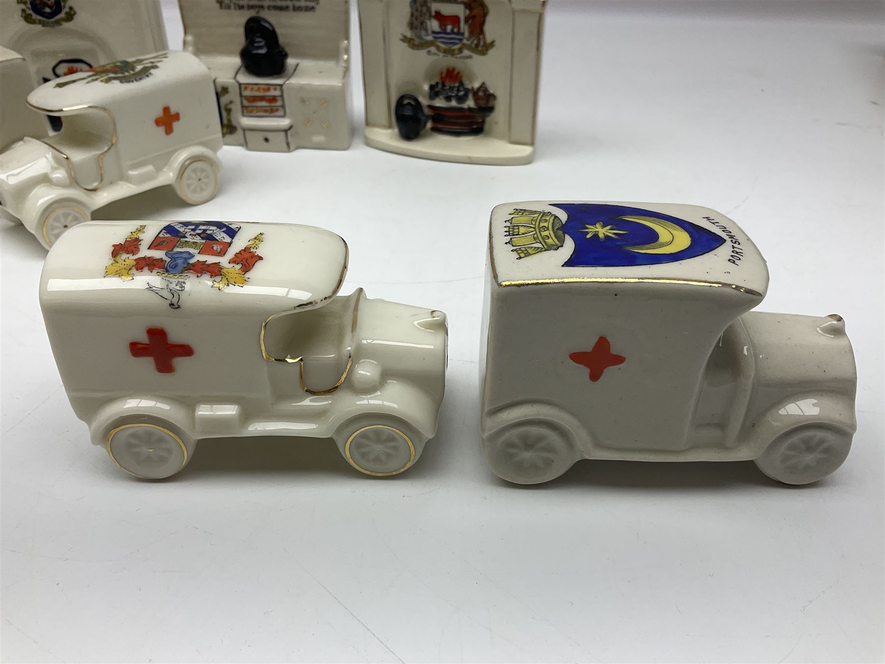 Ten WW1 crested china military models comprising seven field ambulances and three 'Home Fires Burning' fire-surrounds/range; various makers including Willow Art, Arcadian China, Grafton China, Savoy China, Carlton China etc; various crests including Devon, Aldershot, Portsmouth, West Ham, Coventry, Oxford, Hastings, Brighton etc (10)