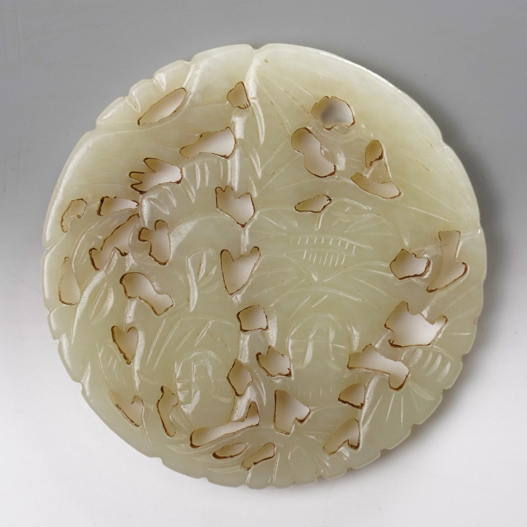 Two carved greenstone roundels, one carved with figures, the other with a dragon, D5.5cm (2)
