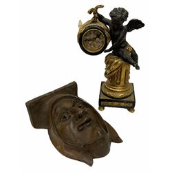 Softwood wall bracket carved with a face, L19cm, together with a composite clock modelled with a winged cherub upon plinth with quartz movement decorated in gilt