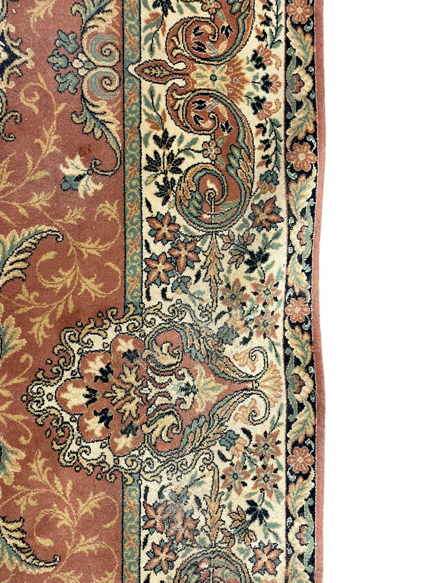 Persian design peach ground carpet, central floral medallion surrounded by scrolling foliage, decorated all over with stylised plant motifs, floral design repeating border