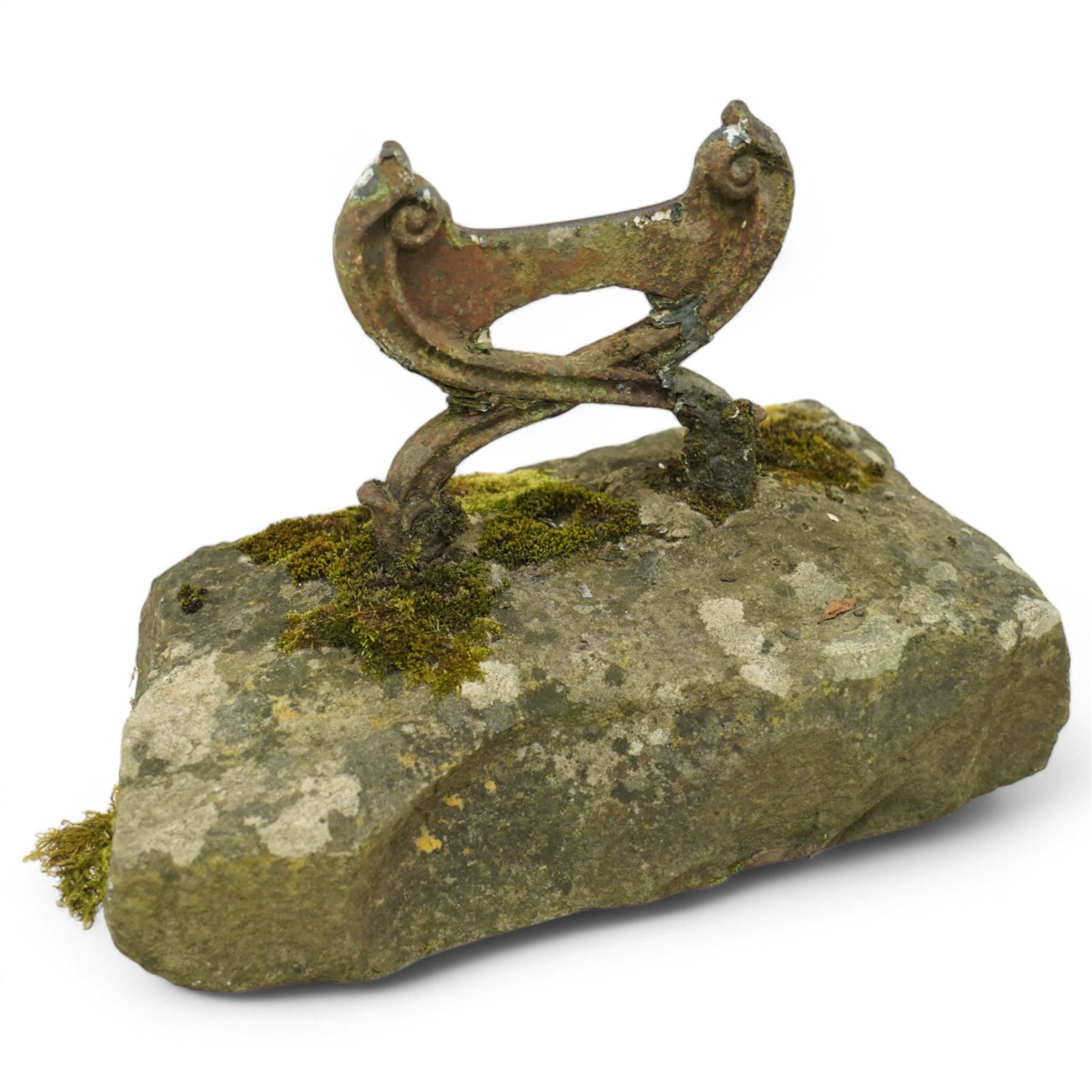 19th century cast iron boot scraper, with scrolled upright mounts, set into a rectangular moss-covered stone base
