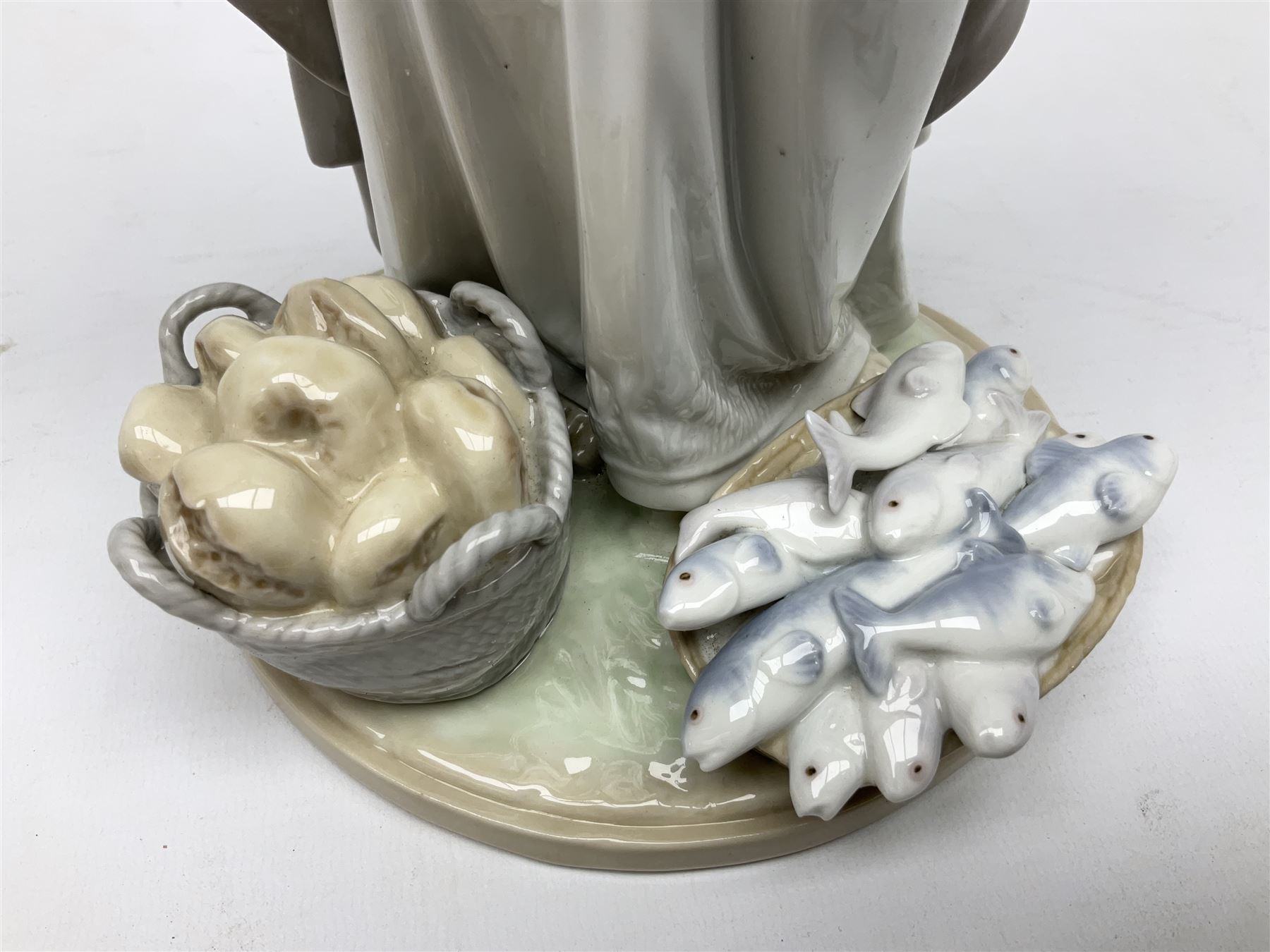 Lladro figure, The Loaves and Fishes, modelled as Jesus Christ with arms raised standing beside a basket of loaves and a basket of fish, sculpted by Salvador Furió, with original box, no 5896, year issued 1992, year retired 1997, H35cm