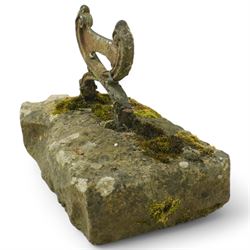 19th century cast iron boot scraper, with scrolled upright mounts, set into a rectangular moss-covered stone base