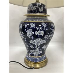 Pair of blue and white table lamps, each of baluster form, decorated with prunus blossom, within stylised borders, raised upon circular gilt base, excluding fittings H48cm