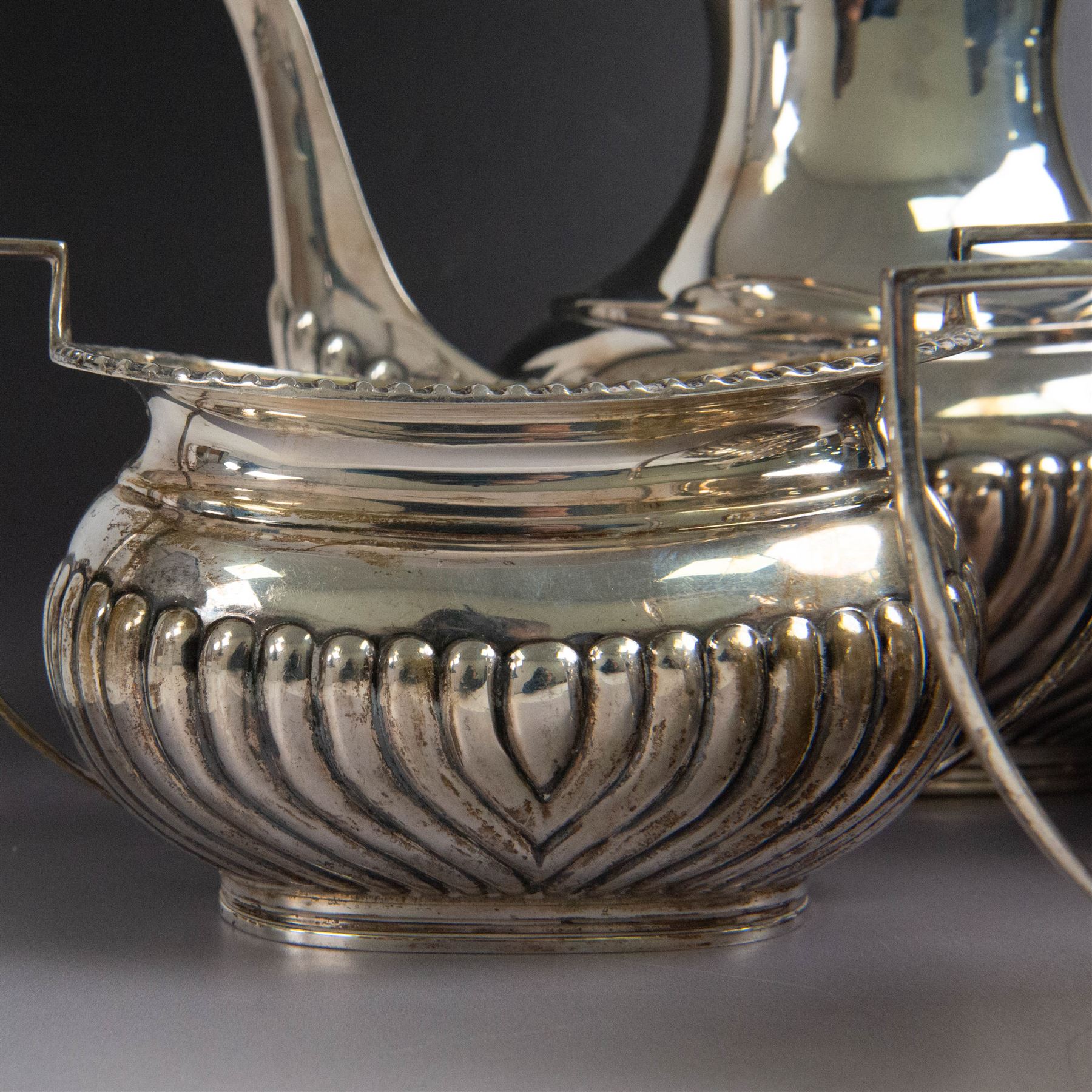 Edwardian silver four piece tea service, comprising coffee pot, teapot, twin handled open sucrier and milk jug, all of oval bellied form, part fluted and with oblique gadrooned rim, with Bakelite type handles and finials to teapot and coffee pot, hallmarked Fordham & Faulkner, Sheffield 1913