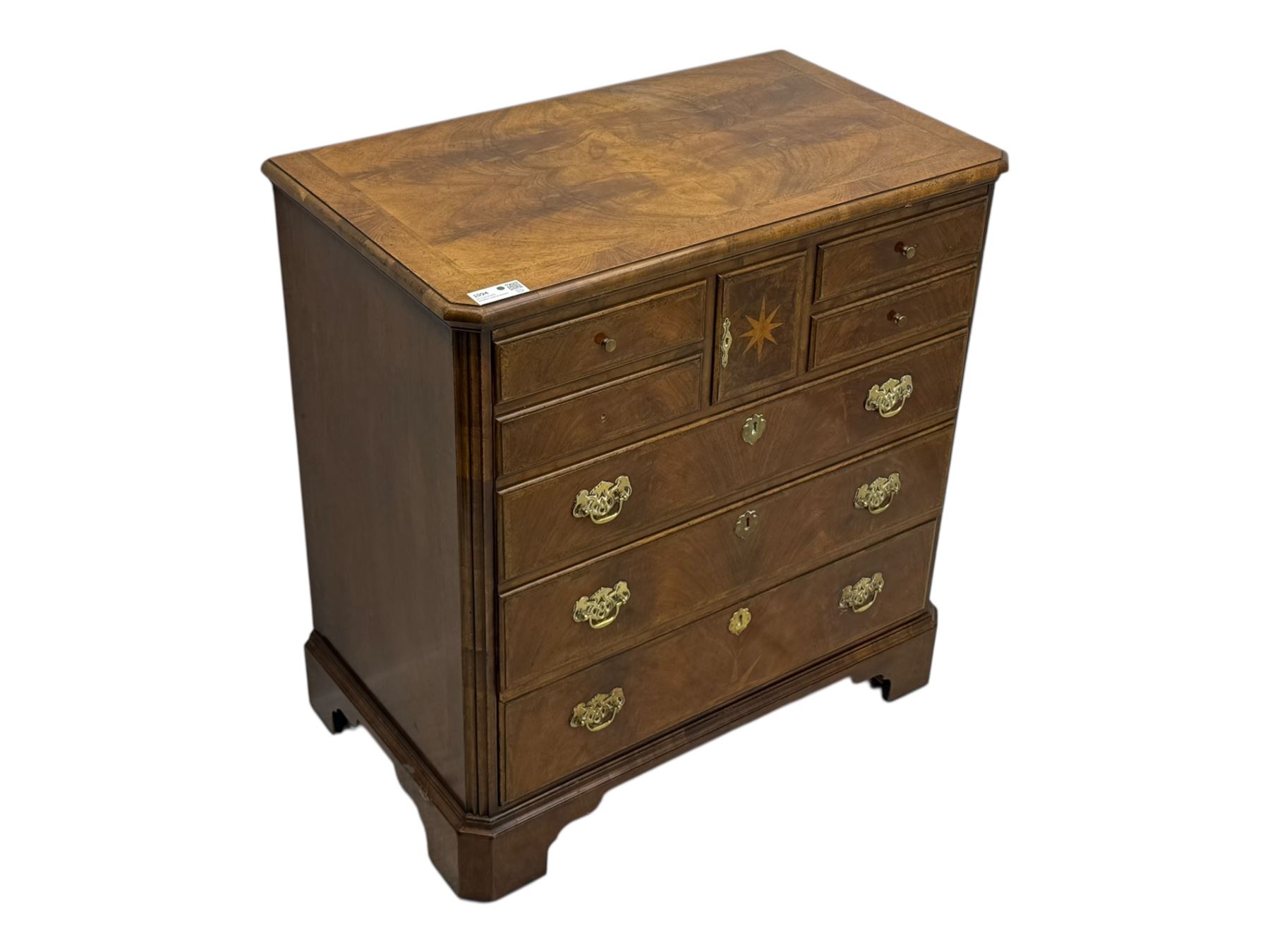 Late 20th century walnut veneered television chest in Georgian style, rectangular top over simulated drawer front with central marquetry star inlay, opening to a shelved TV compartment, lower section fitted with one long drawer, brass handles and ogee bracket feet