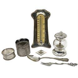Group of silver, comprising silver mounted Art Nouveau desk thermometer, hallmarked J & R Griffin (Joseph & Richard Griffin), Chester 1906, silver mounted and glass pepper grinder, hallmarked John Grinsell & Sons, London 1899, embossed case of cylindrical form with later glass liner, hallmarked Arthur Willmore Pennington, Birmingham 1902, napkin ring with engraved scroll decoration, hallmarked Birmingham, date letter and makers mark worn and indistinct, money clip stamped 925, teaspoon marked Sterling, and Continental pickle fork marked 8305. 