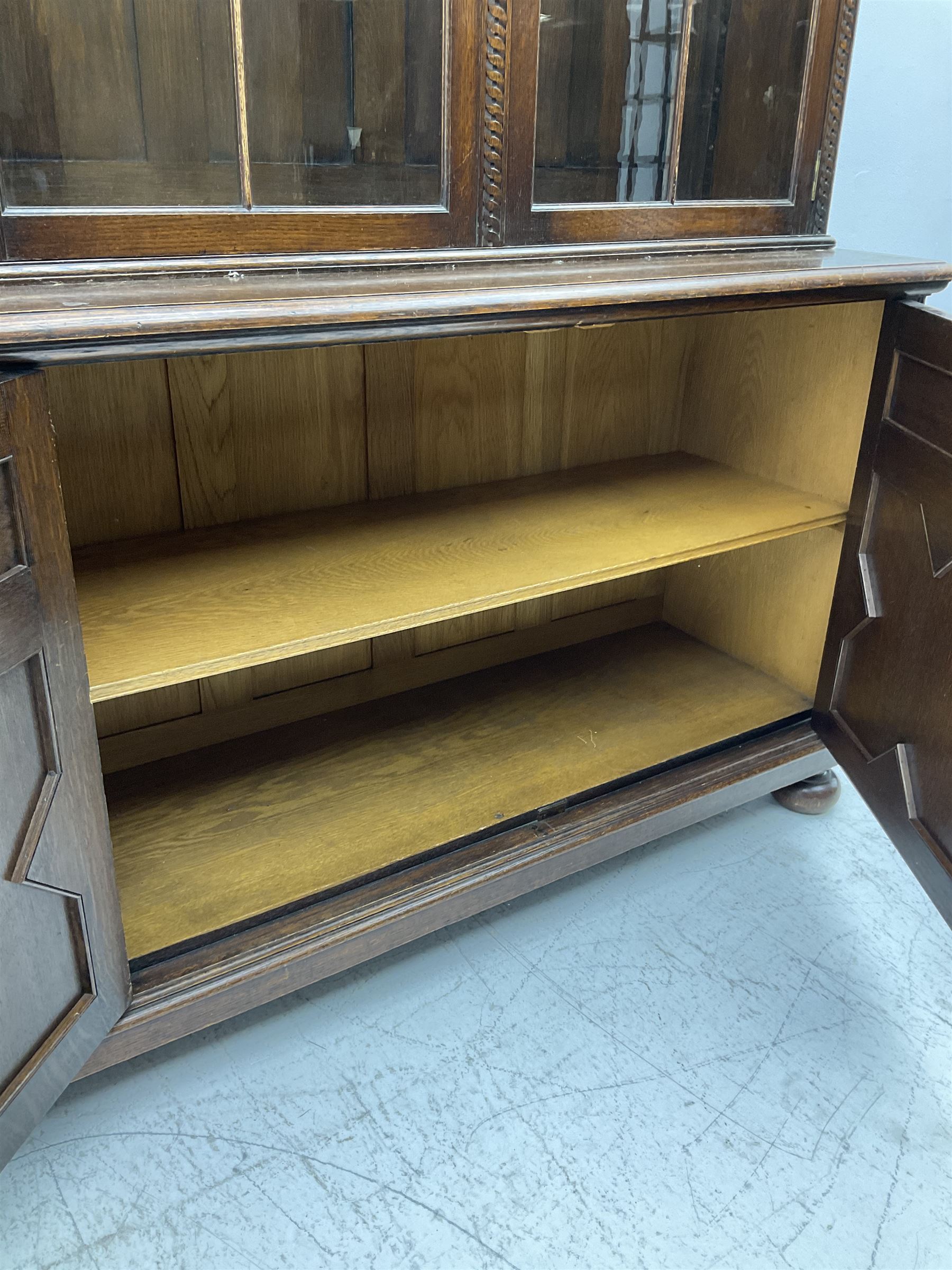 Waring and Gillow - oak bookcase on cupboard, projecting cornice over arcade frieze, guilloche upright decoration, the top section enclosed by three astragal glazed doors, the lower section enclosed by three geometric panelled doors with blind fretwork decoration, on turned feet