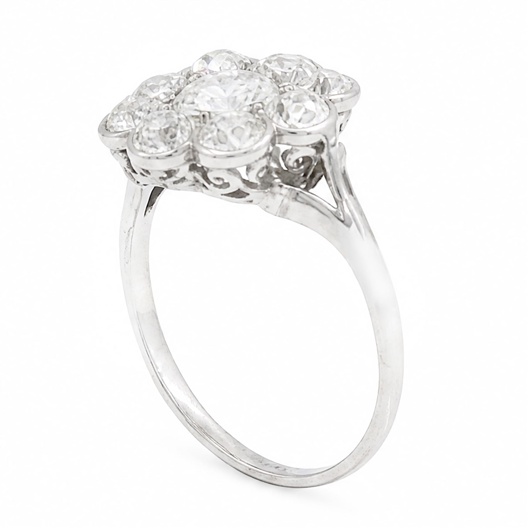 Early 20th century platinum diamond daisy flower head cluster ring, principal round cut diamond of approx 0.65 carat, surrounded by eight milgrain set old cut diamonds, within a pierced scroll design gallery, total diamond weight approx 2.15 carat