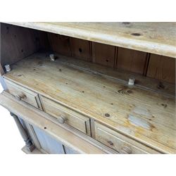 Early 20th century pine kitchen dresser, featuring a hutch with arched top over three open shelves, the base with five drawers over three cupboard doors, turned column supports flanking the doors, scalloped apron base with bracket feet