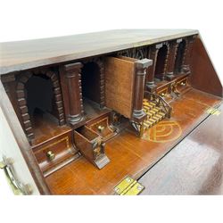 Georgian figured mahogany miniature bureau on stand - the fall front bureau with well fitted interior featuring a combination of thirteen sliding parts, central mirrored fret work door with leading chequered inlaid steps, flanked by a series of bricked arches and Doric columns, fitted with two drawers, the lower drawer with star inlay, lower moulding over ogee bracket feet, brass carrying handle to each side. The stand in figured mahogany with moulded lipped top, square supports with outer mould and inner chamfer joined by shaped undertier