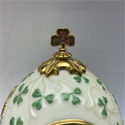 Franklin Mint The Emerald Isle Collector Egg, the egg decorated with embossed shamrocks upon a cream ground, with a gilded shamrock finial, accents and openwork door, opening to reveal a miniature landscape scene, upon three gilded feet set with green paste stones, with certificate of authenticity H23cm, 