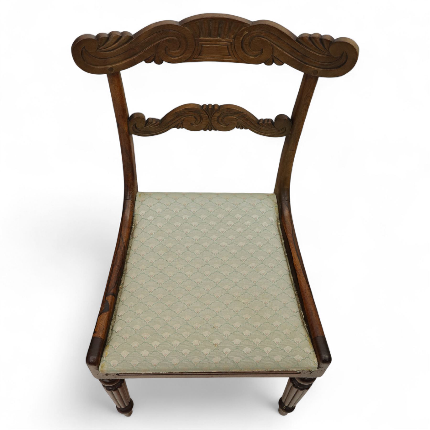 Set of four 19th-century rosewood dining chairs in the William IV style, shaped and carved top rail with fan and scroll decoration above a upholstered padded seat on reeded and turned front legs 