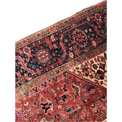 Persian Heriz red ground carpet, large stylised pole medallion surrounded by Pitrak motifs, indigo ground border decorated with stylised flower heads and trailing leafy branches, within floral pattern guard stripes