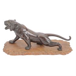 Japanese Meiji period bronze, modelled as a crouching tiger, its head raised in a roar, with glossy stripes and naturalistic mane, with seal mark for Mitsumoto saku, upon a carved softwood stand, bronze H20.5cm L46cm
