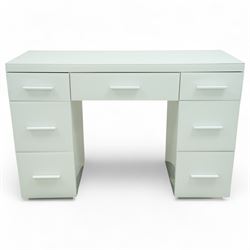 Contemporary white and glass twin pedestal dressing table and two matching bedside chests, dressing table with rectangular top above seven flush-front drawers arranged around a central kneehole, with white matching pulls, bedside chests each with square top over three drawers with integrated handles, plain sides and plinth bases

Bedside tables (W 121cm D 41cm H 82cm)
Dressing table (W 45cm D 45cm H 66cm)