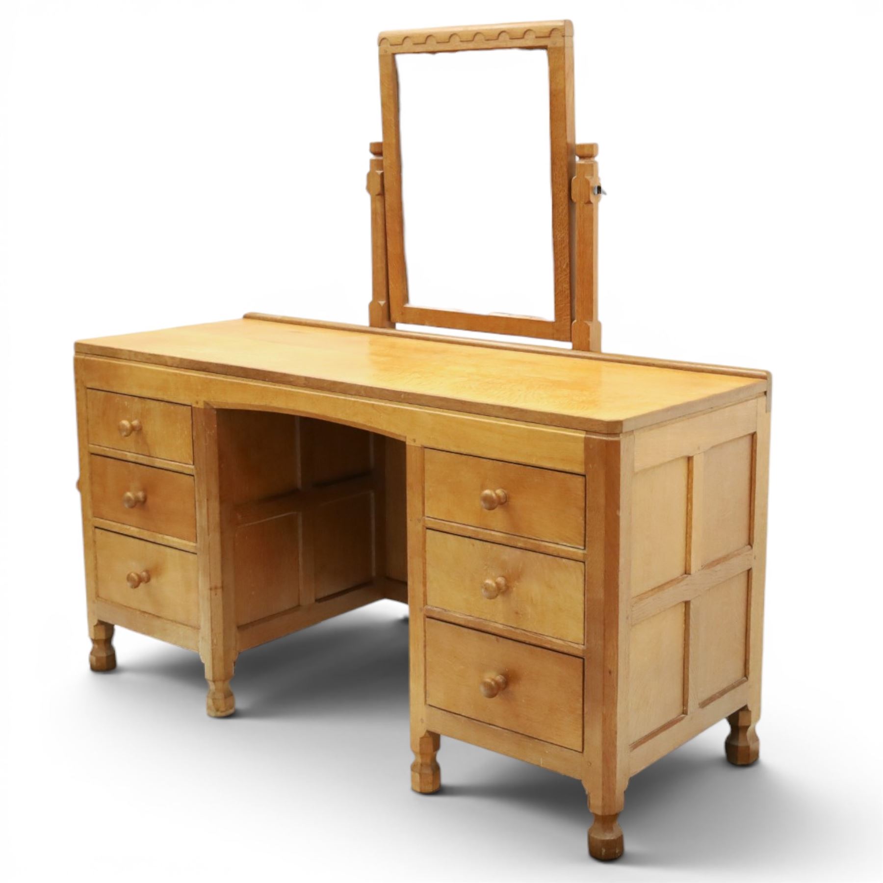 Mouseman - adzed oak kneehole dressing table with mirror, the rectangular adzed top with raised back and canted corners with fixed central pivoting mirror with scallop-carved cresting rail, over an arched recessed kneehole flanked by three graduating drawers to each side with turned knob handles, raised on octagonal feet, with carved mouse signature, by the workshop of Robert Thompson of Kilburn