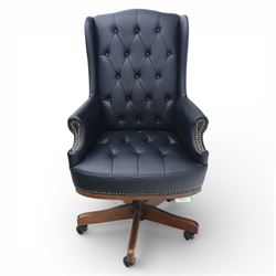 Chesterfield style desk chair upholstered in black, brass studded trim with tall button backed seat, with faux wooden base raised upon castors