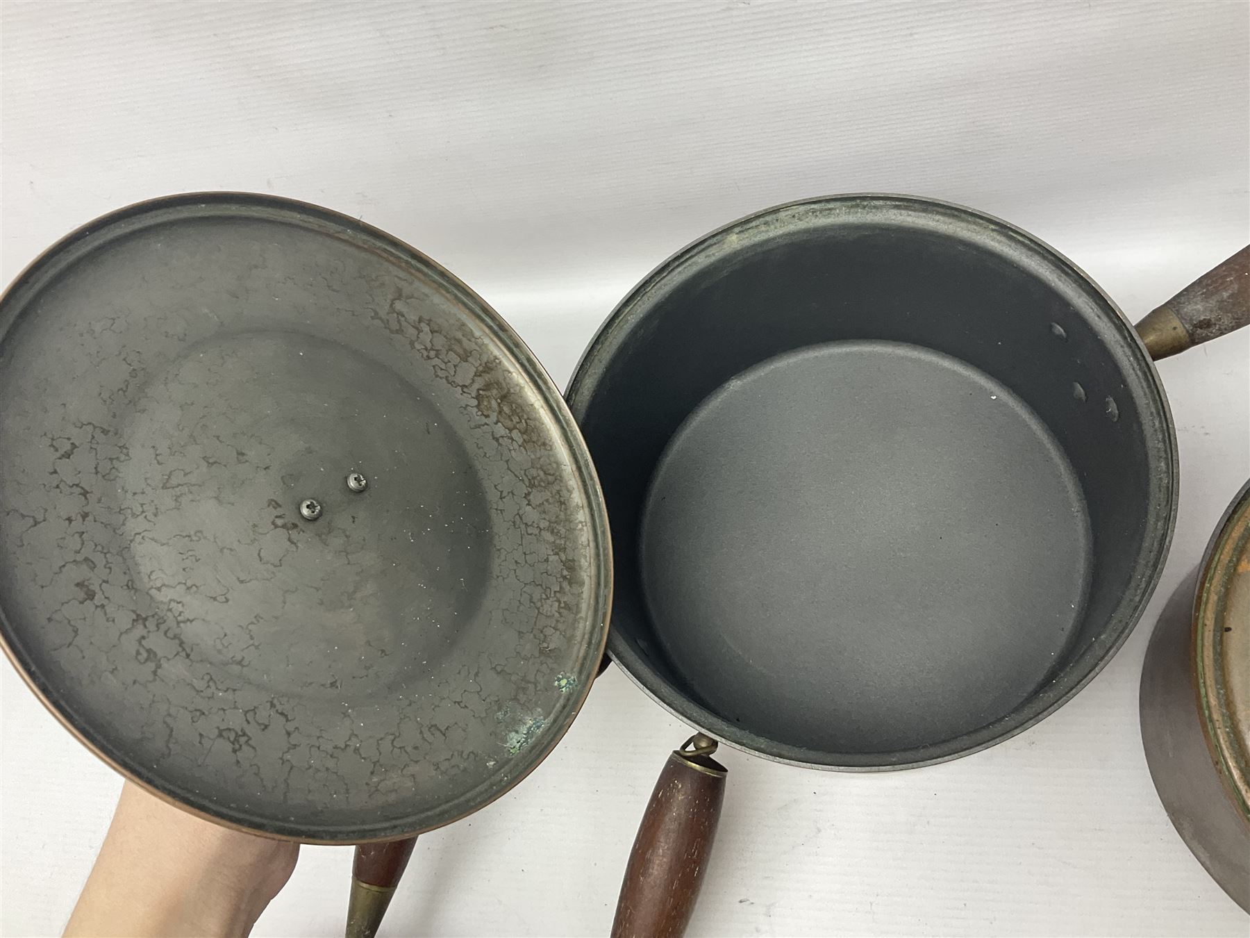 Four Victorian copper moulds, together with a graduating set of copper pans with wooden handles and finials to covers, largest pan 