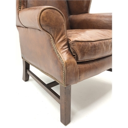  George lll  style wing back chair,  upholstered in brass nailed antique brown leather with loose seat cushion on square supports joined by stretchers  