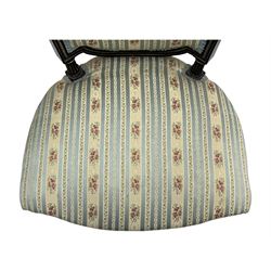 19th century French ebonised low chair, upholstered in floral striped fabric within a moulded frame with gilt line and foliate decoration, the seat of serpentine form, raised on turned fluted legs with toupie feet