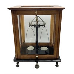Set of laboratory balance scales by Reynolds & Branson of Leeds in fully glazed mahogany case with rise-and-fall front door, black vitrolite base with brass feet and hand cranked action L40cm H51.5cm D30cm; and bakelite cased set of brass weights