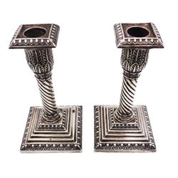 Pair of Edwardian silver candlesticks, each with acanthus detailed capital and removable beaded square nozzle, upon a twisted column and filled square stepped base, hallmarked Walker & Hall, Chester 1907, H14.5cm