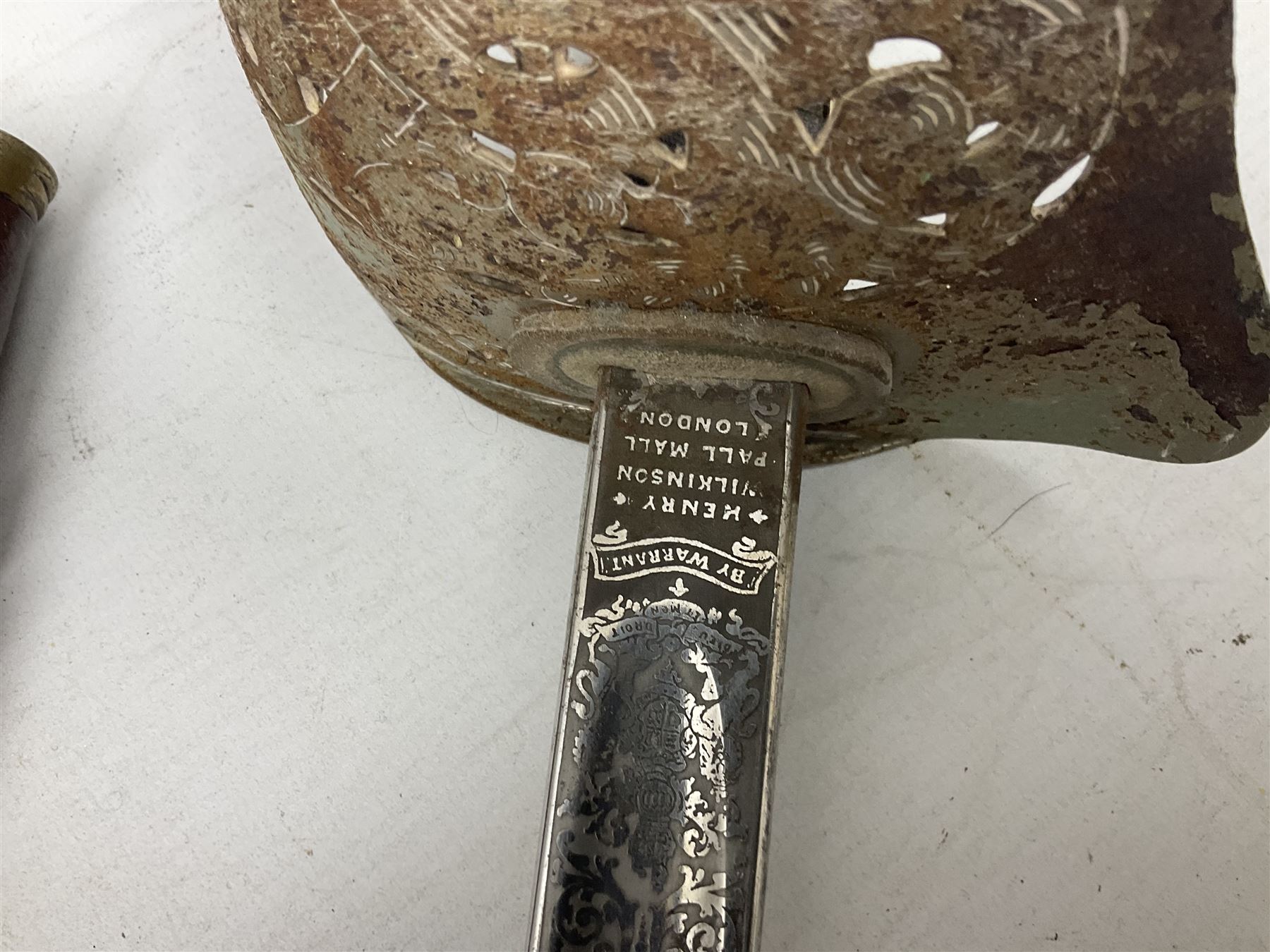 George V 1897 pattern Army Officer's sword by Henry Wilkinson Pall Mall London, the 82.5cm 'London Made' blade etched to both sides with Royal Crests and cyphers etc, pierced half-basket hilt with wire-bound fish skin grip and remains of leather knot strap; in leather covered field service scabbard L101cm overall; and two 14th Prince of Wales Own swagger sticks (3)