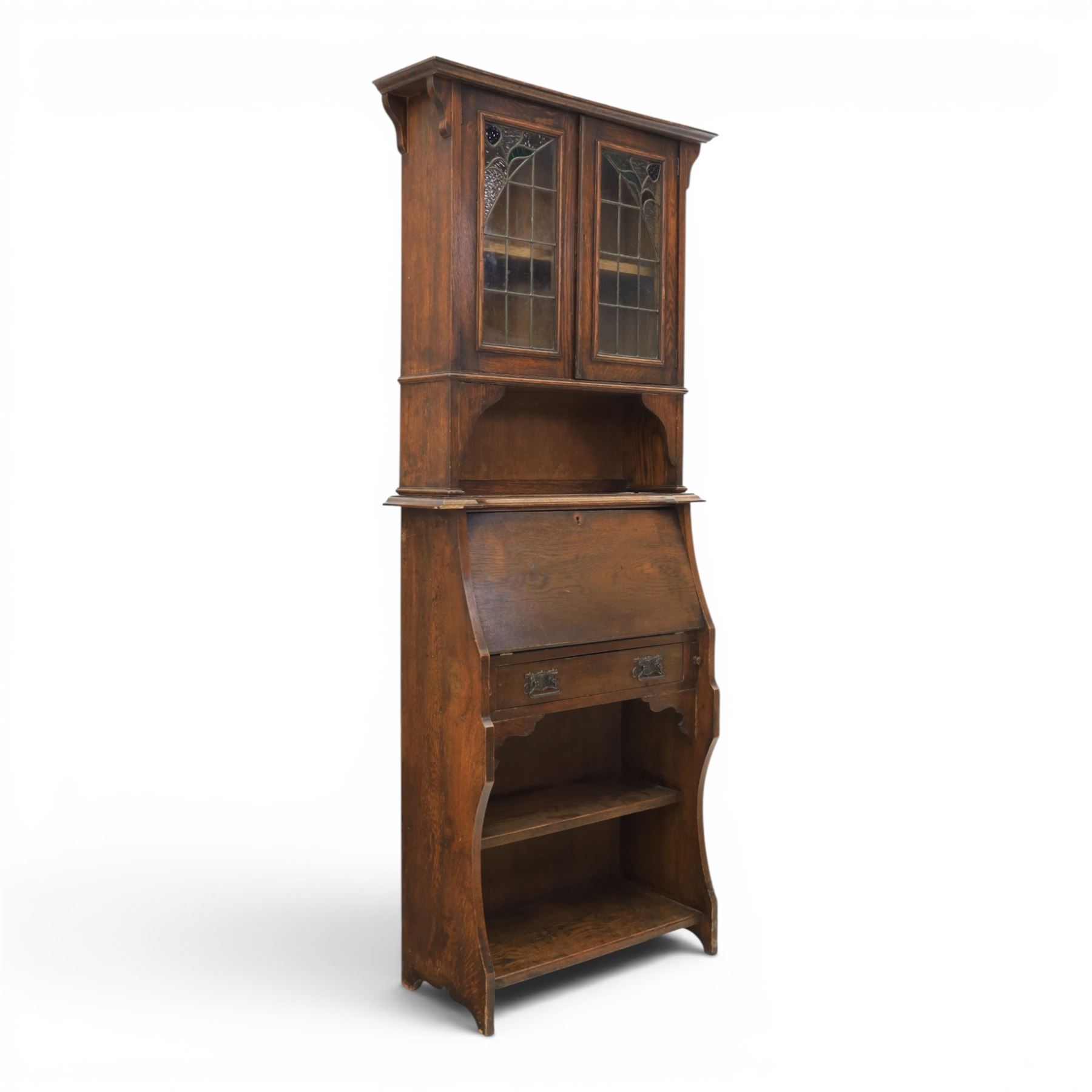 Arts & Crafts oak bureau bookcase, projecting cornice with leaded and glazed upper cabinet, the lower section with fall front section revealing a fitted interior, above shaped lower shelving 