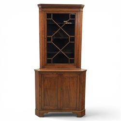 19th century oak floor-standing corner display cabinet, dentil cornice above astragal glass, shaped fixed shelves, the lower section with twin cupboard doors, on shaped bracket feet