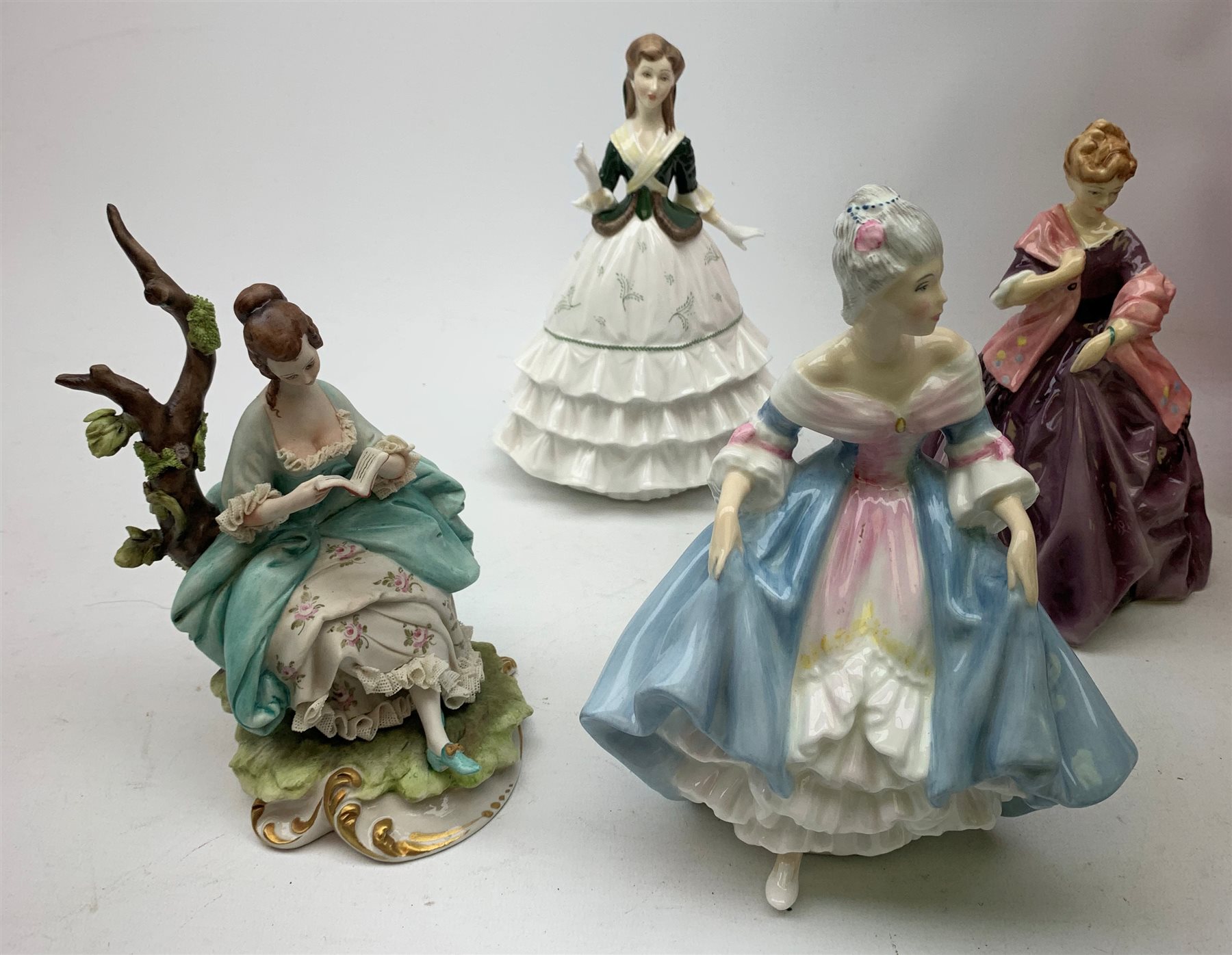 A group of figurines, comprising two boxed Spode Pauline Shine examples, Lily and Olivia (one a/f), a Royal Douton figurine First Dance modelled by F G Doughty, a further Royal Doulton figurine, Debutante, a Royal Doulton figurine, Southern Belle HN2425, and an unmarked continental figurine. 