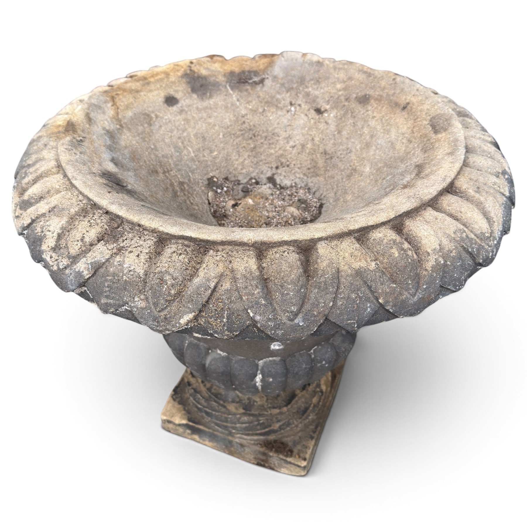 Set of three 19th century weathered carved sandstone garden urns of Neoclassical campana form, the broad everted rim carved with pointed egg-and-dart motifs, above a plain waisted bowl with gadrooned underbelly, on moulded rope-twist socle and square plinth base