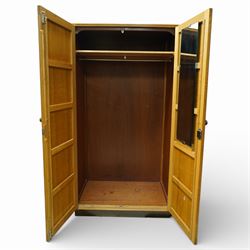 Mid 20th century oak veneered wardrobe, the plain rectangular top above a pair of hinged doors fitted with circular handles, opening to reveal a hanging rail and upper shelf, one door with inset mirror, the whole raised on a plinth base