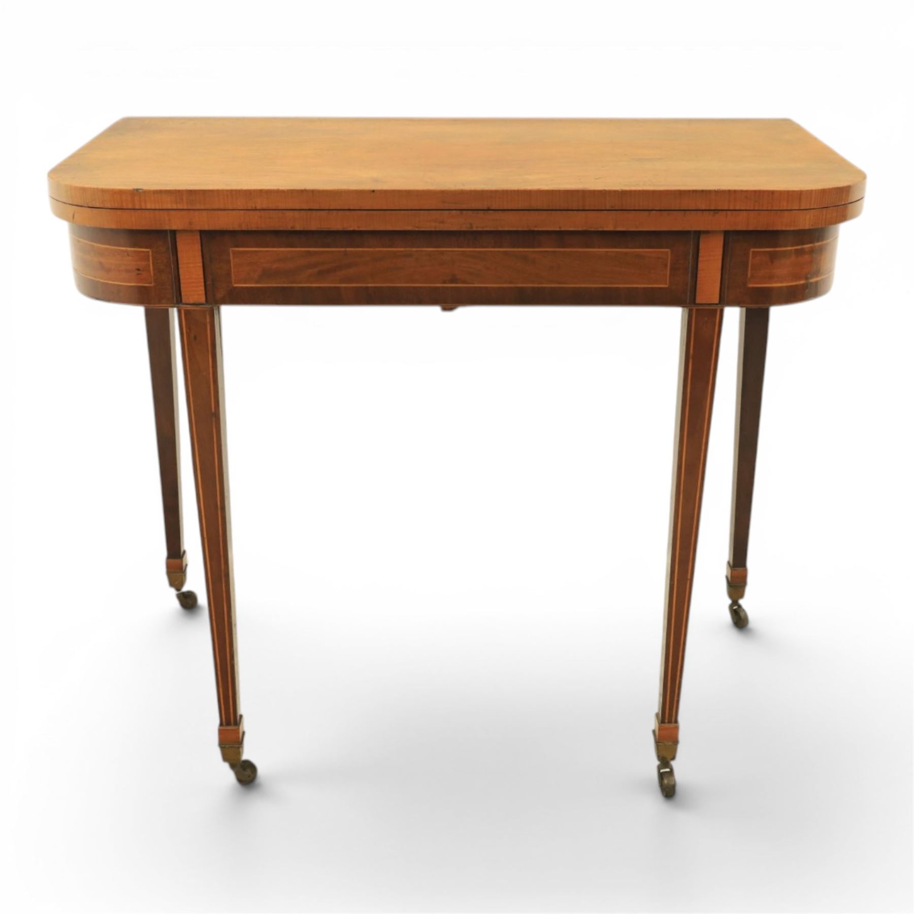 Regency mahogany fold-over tea table, rounded rectangular top with gateleg action, inlaid and crossbanded frieze, raised on squared tapering supports on brass castors