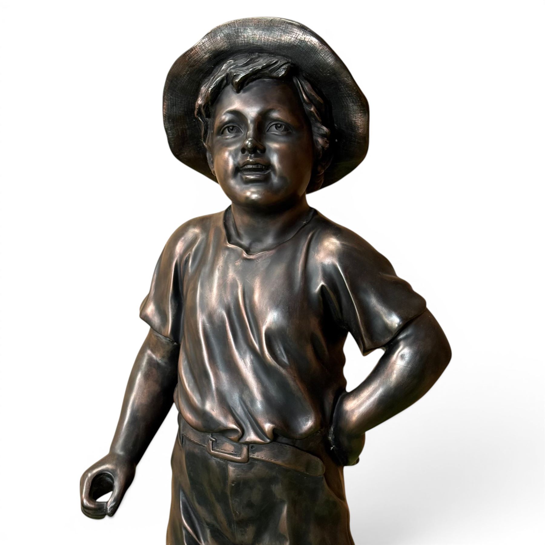 Bronzed composite figure of a boy wearing a hat, on circular plinth