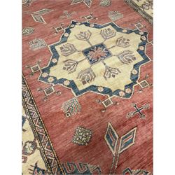 Persian rug, central medallion on red field decorated with geometric motifs, the border decorated with repeating stylised plant motifs 