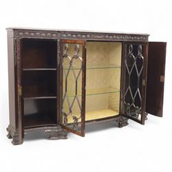 Edwardian mahogany serpentine breakfront display cabinet in the neoclassical style, the rectangular top above a carved frieze with roundels, foliage, and ribbon tied swags with central bow-fronted astragal glazed doors enclosing shelves, flanked by panelled doors, raised on bracket feet 