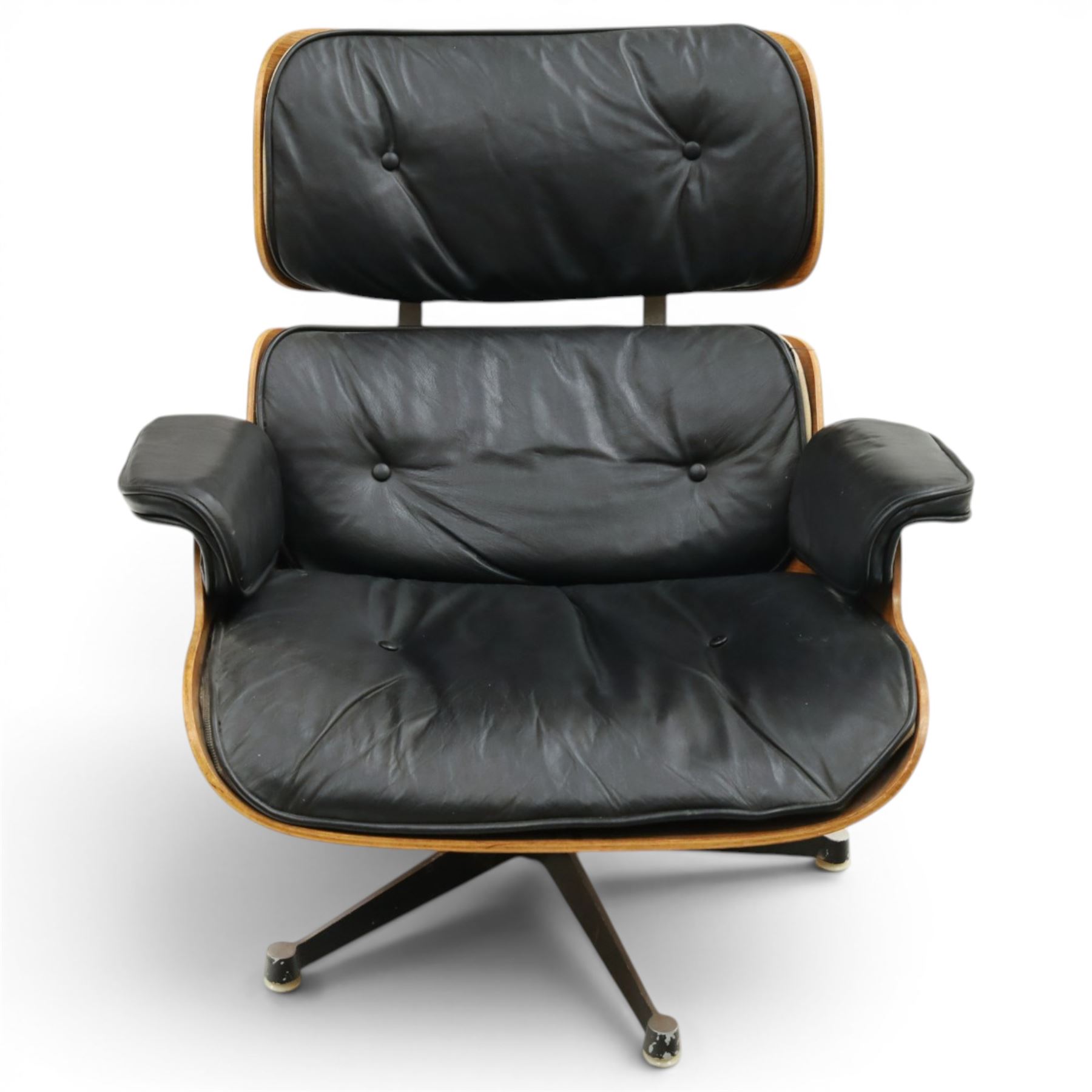 Charles and Ray Eames for Herman Miller - lounge chair, moulded veneered plywood shell with buttoned black leather upholstery, separate headrest and back cushions, padded armrests, on black cast aluminium five-star swivel base, manufactured under licence by Hille of London
