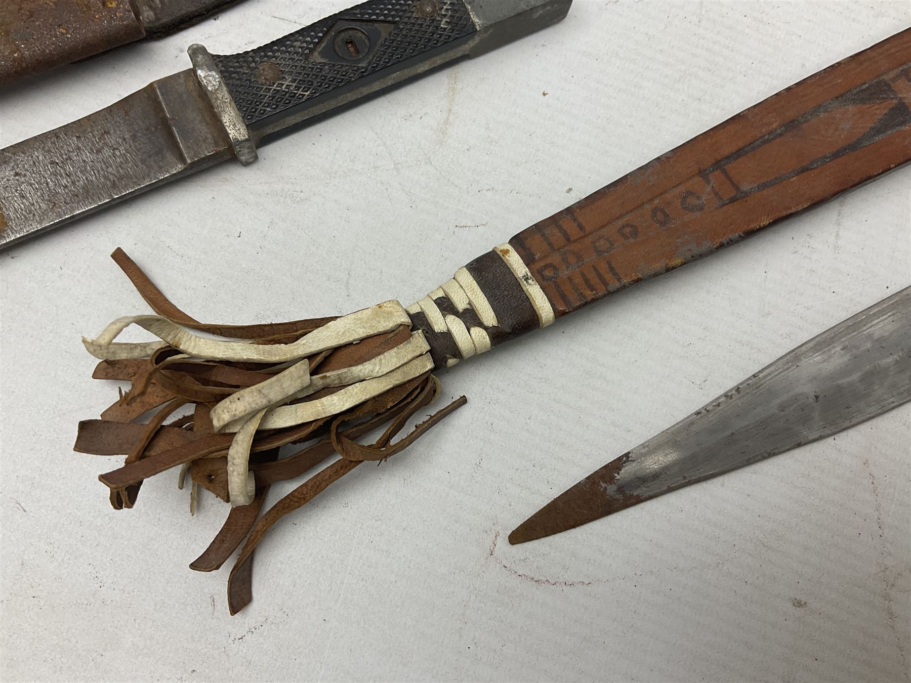 Indian kukri with 29cm curving steel blade and nickel mounted horn grip; in leather covered scabbard with one skinning knife L42cm overall; Hitler Youth knife with scabbard in relic condition; and three African graduated knives each with crudely carved wooden grips and painted leather covered scabbards (5)
