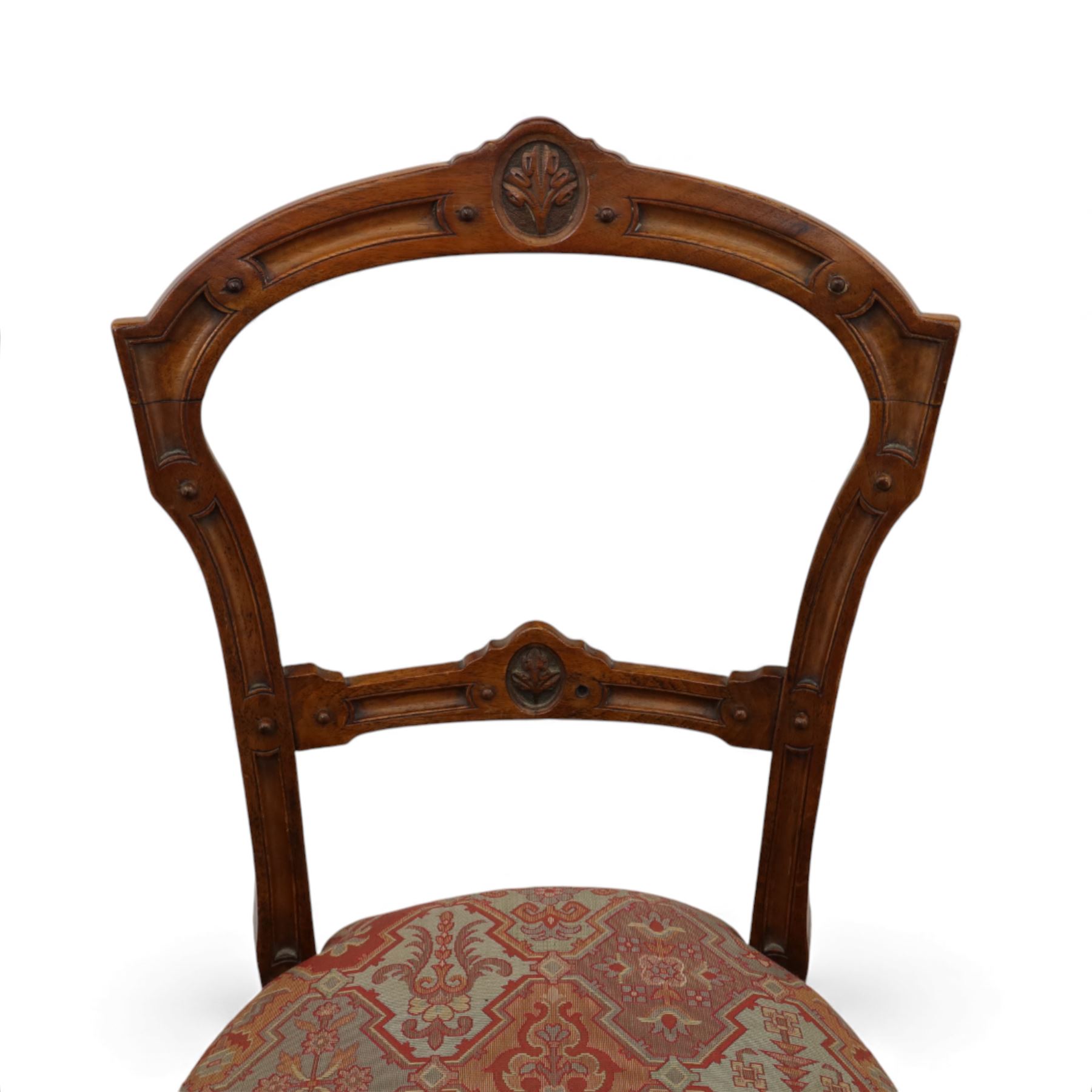 Set of six late Victorian mahogany dining chairs, the shaped top rails carved with anthemion motifs, above pierced splats, floral and geometric fabric seat, on turned and fluted front legs