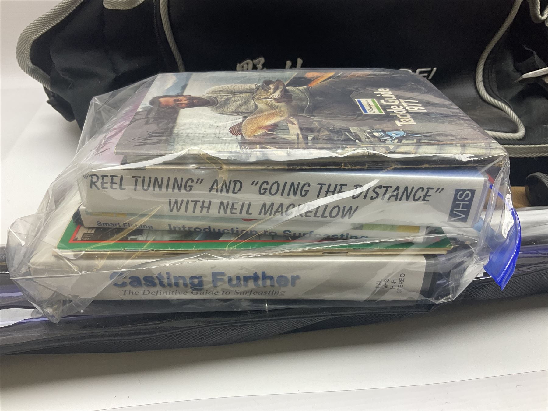 Collection of fishing memorabillia and equipment, including an Allcocks three piece split cane trout fly rod, Shakespeare Salt 3600 surf rod, two tackle bags, Old Red Seastreak multiplier reel, Sportext Saltwater fixed spool reel, fishing dvds, etc