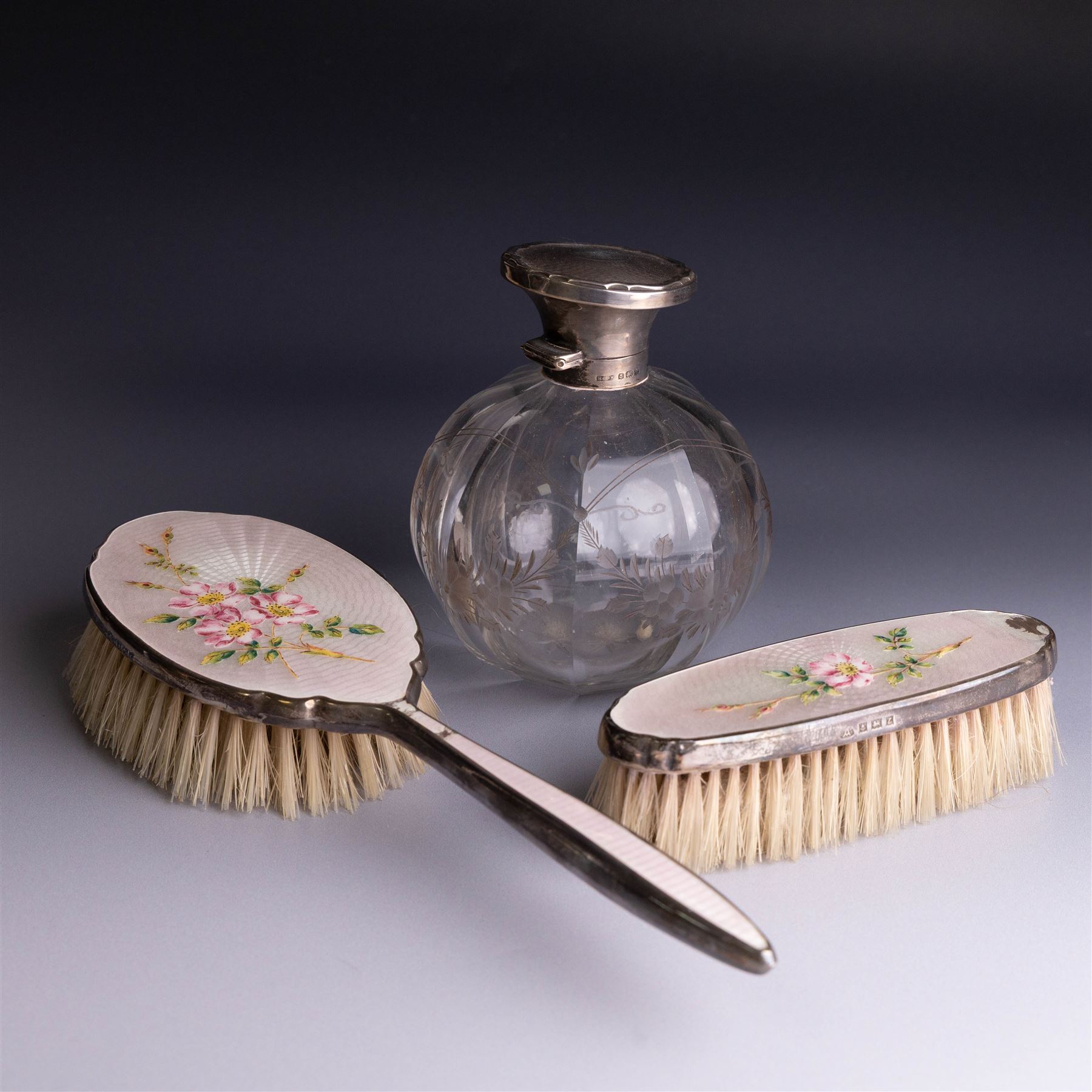 Mid 20th century silver mounted hairbrush and clothes brush, with guilloche enamel floral decoration, hallmarked Adie Brothers Ltd, Birmingham 1960, together with an silver mounted glass scent bottle, the glass with etched floral decoration and engine turned cover, hallmarked 
