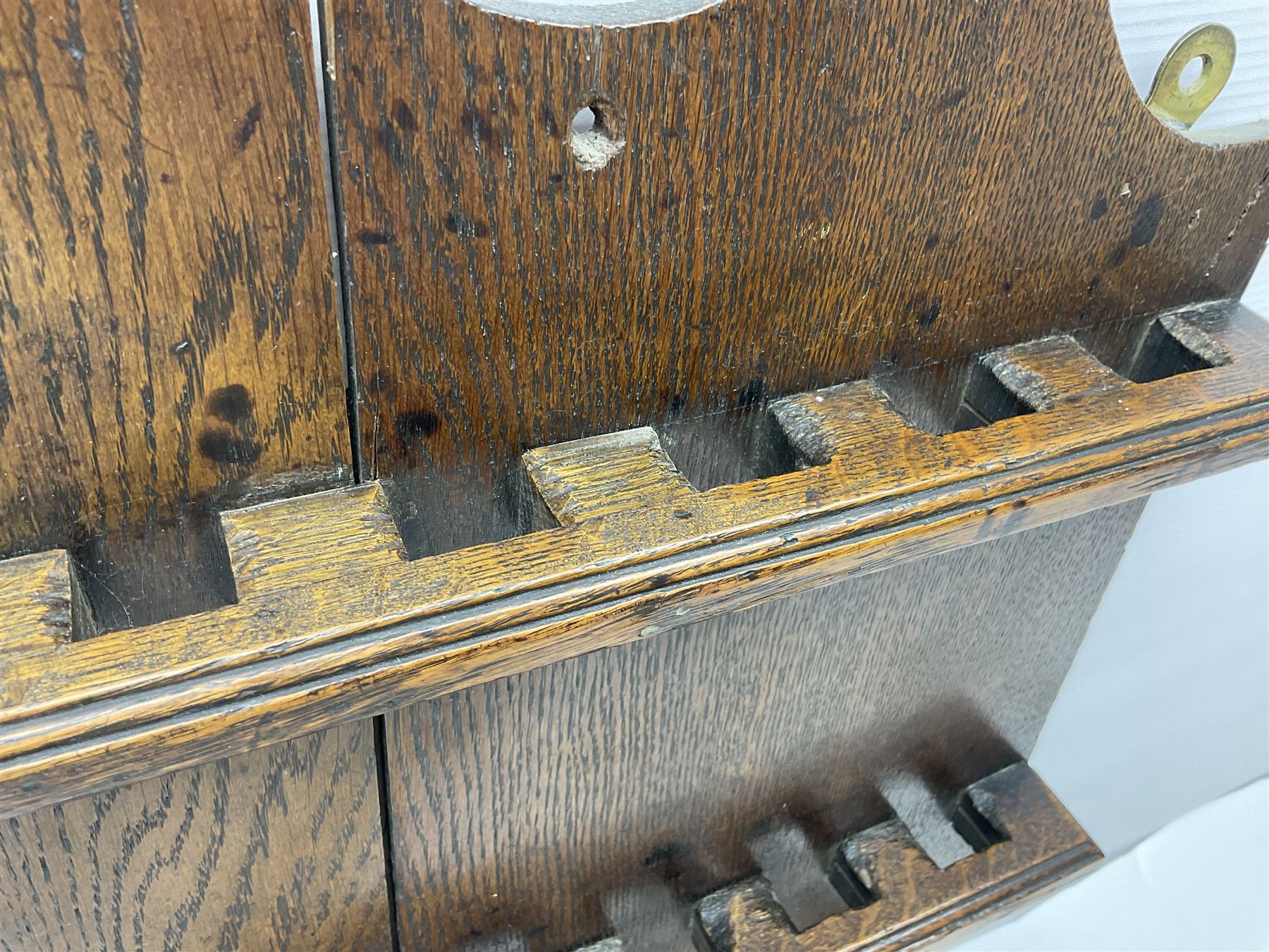 George III oak spoon rack and candle box, the rectangular backplate with shaped  pediment and two six aperture spoon racks, above a candlebox with hinged cover, with various brass spoons and a pair of brass candle snuffers, H56.5cm, W35cm, D14cm 