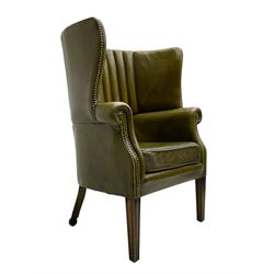 George III design barrel back armchair, upholstered in olive green leather with studwork, vertically cushion ribbed interior and integral armrests, raised on square tapering supports with rear castors