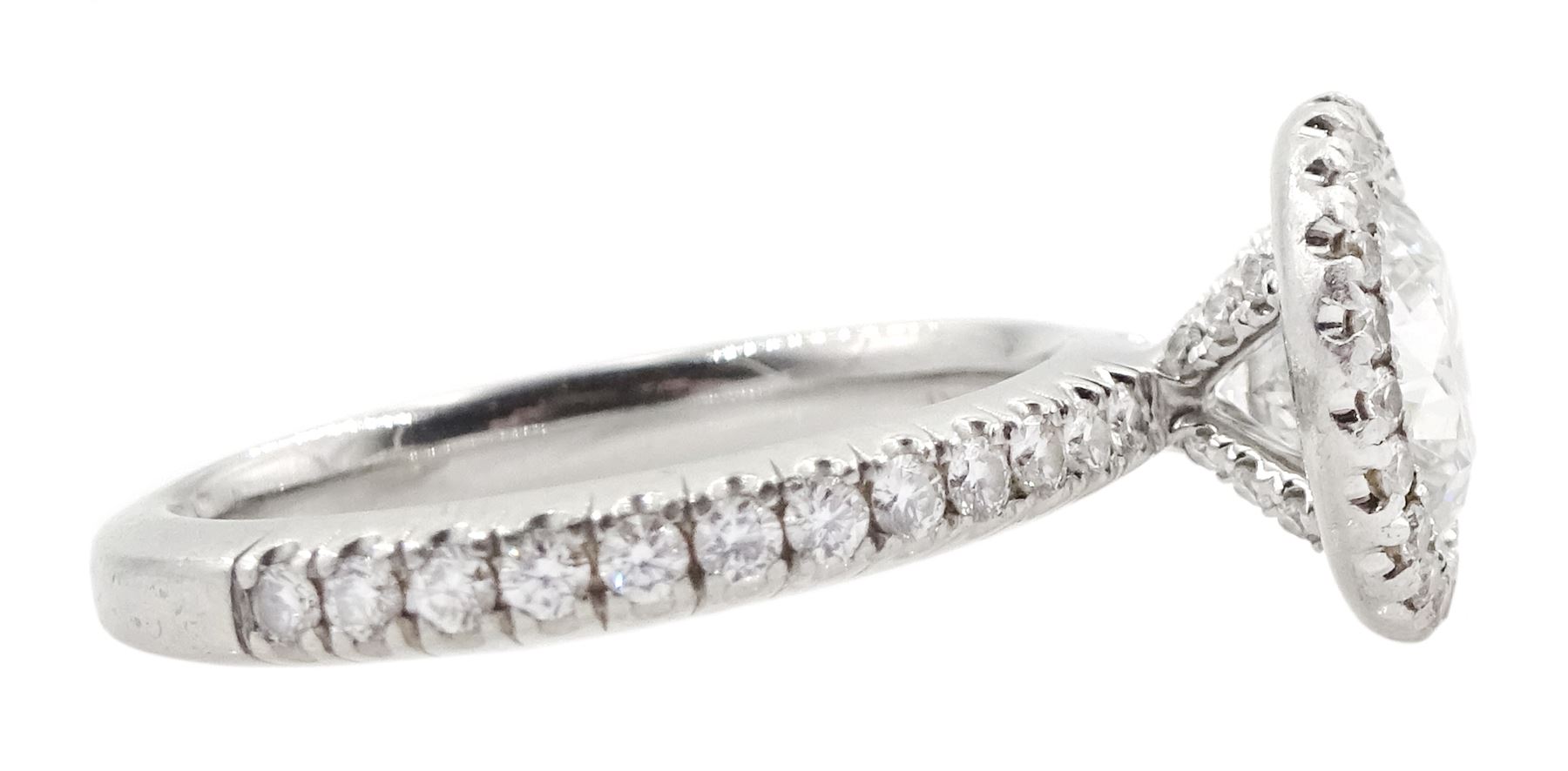 De Beers Aura platinum round brilliant diamond ring, the central diamond solitaire of 1.07 carat, clarity VVS2, colour E, with GIA certificate, surrounded by halo of diamonds and diamond set shoulders, total diamond weight 1.46 carat boxed with authenticity card and purchase receipt dated 2017