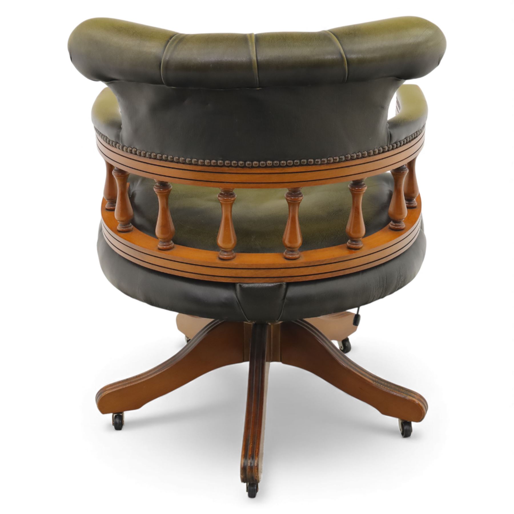 Late 20th century swivel captain’s desk chair, green buttoned vinyl upholstered back and seat with brass stud edging, the spindle gallery over a rotating base with five splayed supports on castors