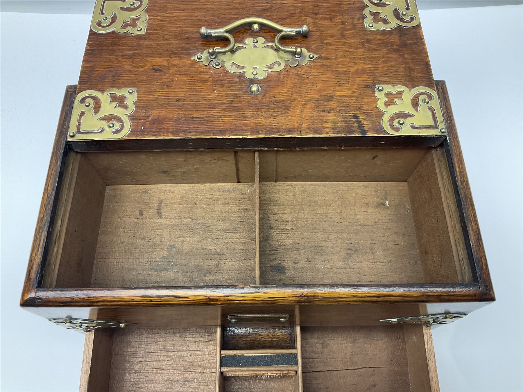 Brass mounted oak humidor, the slide action top opening to a base drawer, cedar lined with central compartment and striker, the drawer stamped Rd 107198, H17cm, D18cm